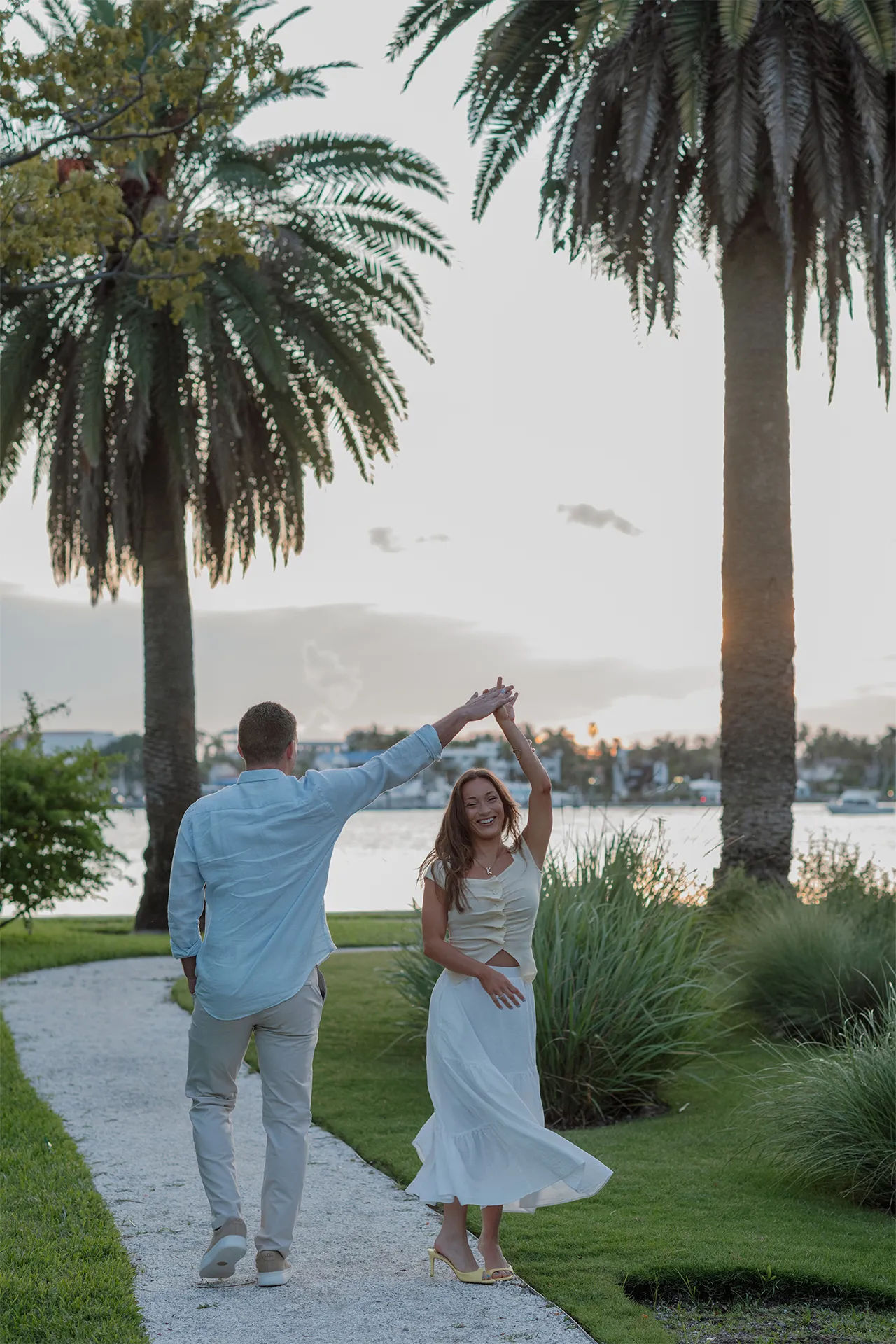 Couple walking hand-in-hand along a palm-lined path after a beach engagement in Palm Beach.