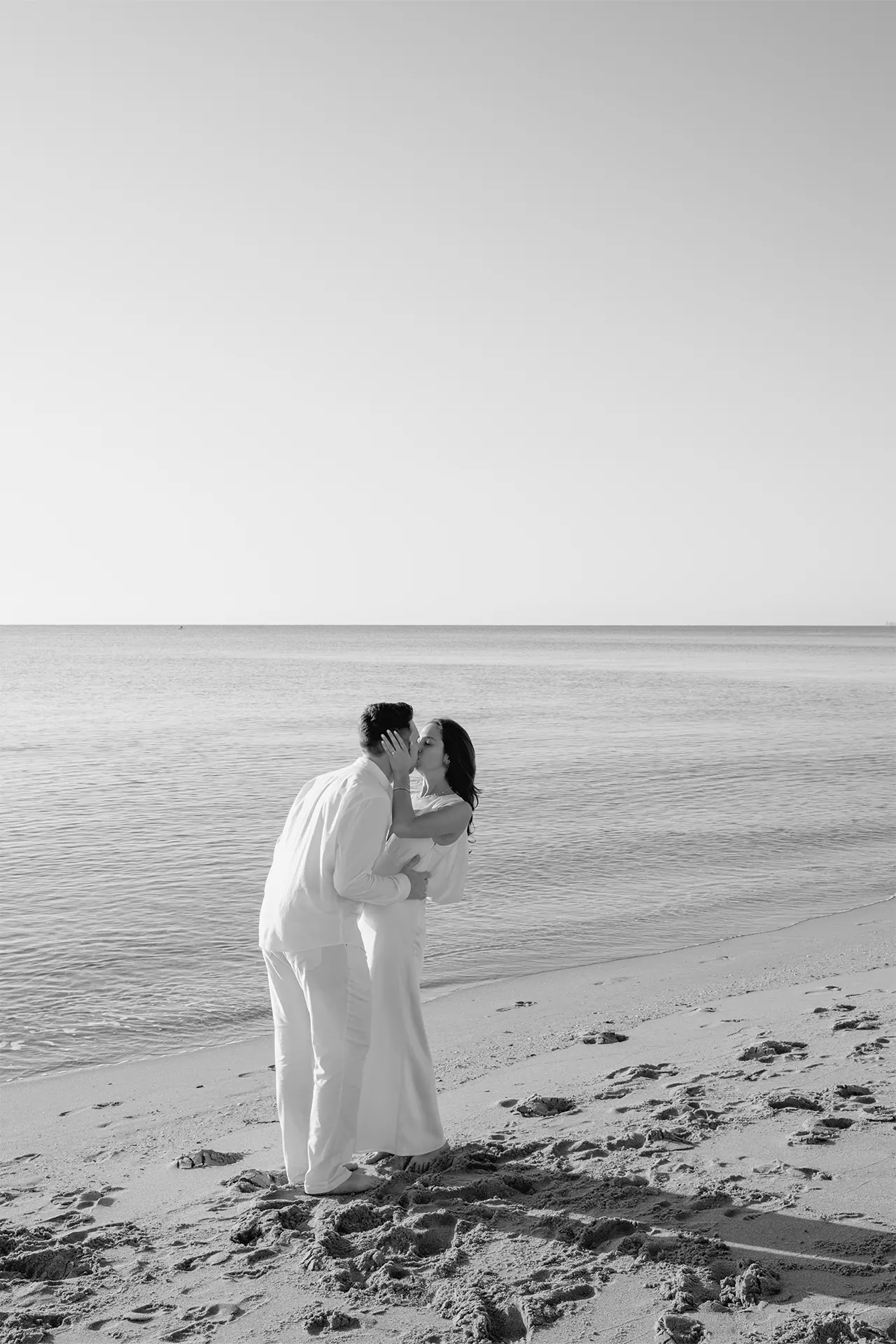 Timeless black and white photo of a romantic kiss by the ocean