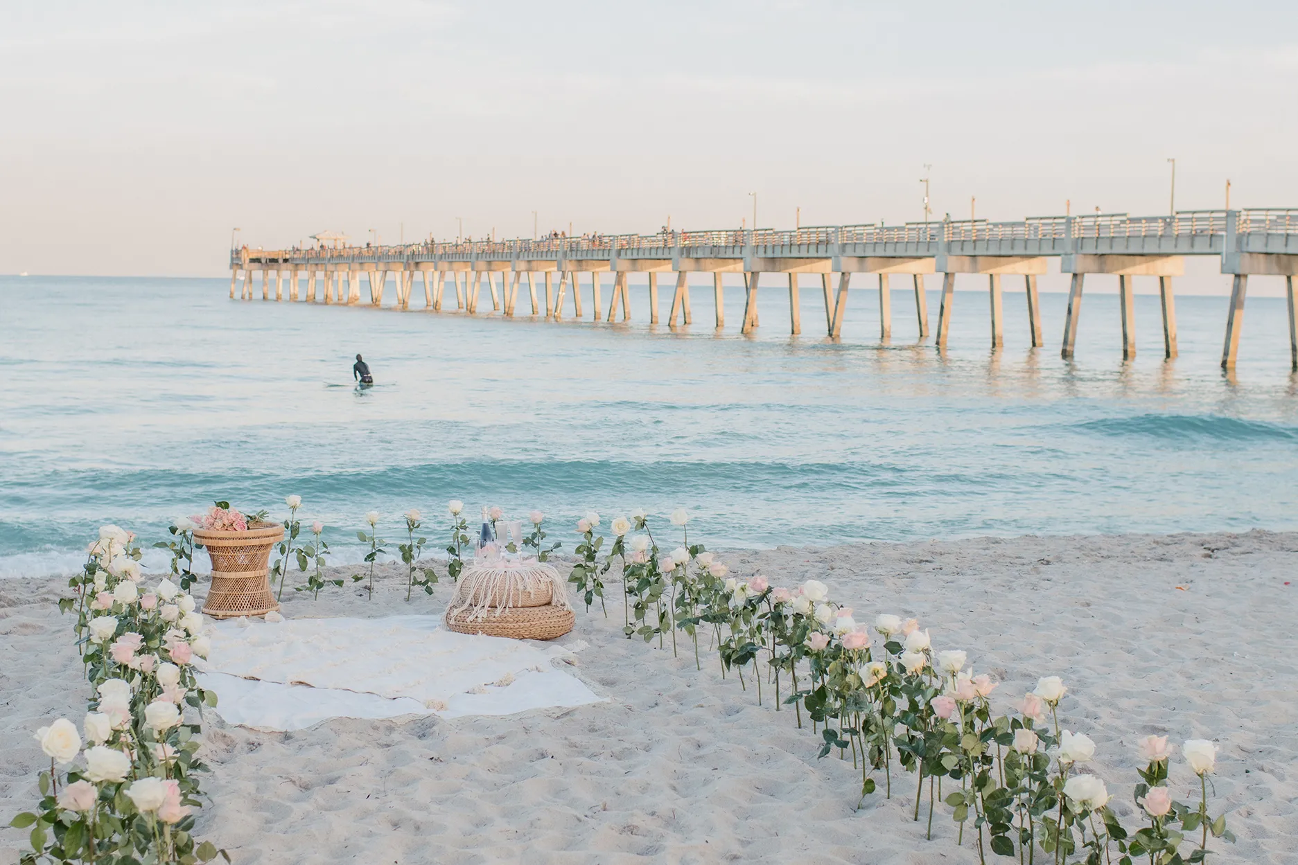 Full view of the romantic boho-chic picnic setup on the sand for the proposal