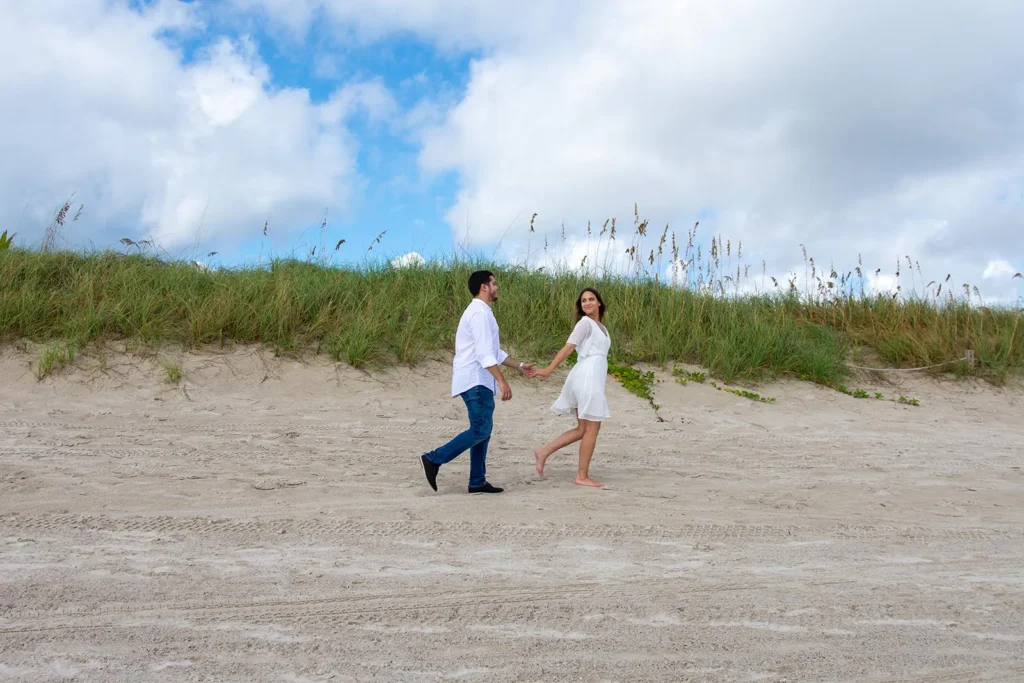 Beach Engagement Session capturing the couple walking through the sand at South Pointe Park