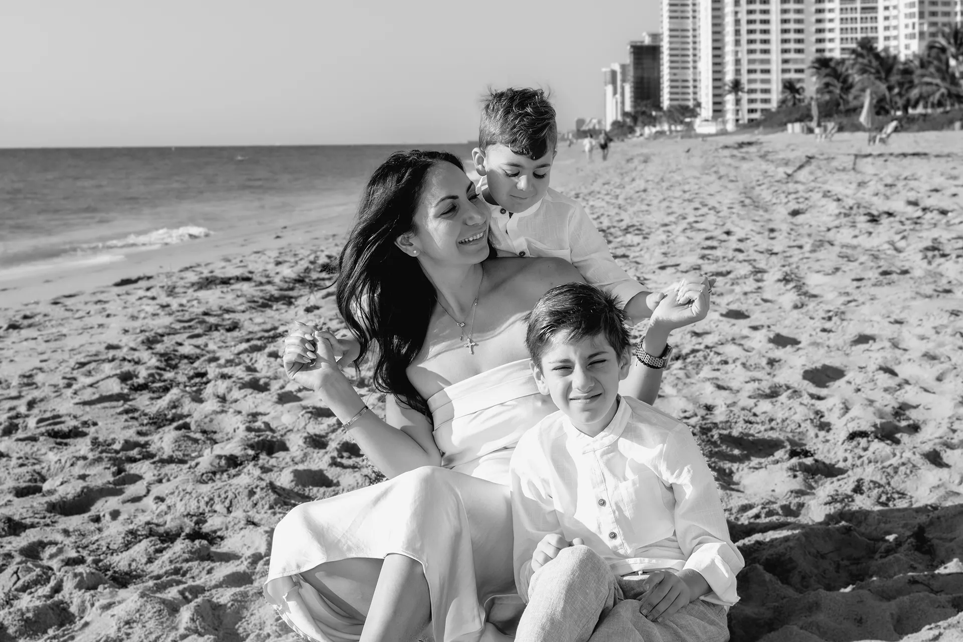 Affectionate moment of a mom embracing her sons at sunrise in Lauderdale-by-the-Sea.