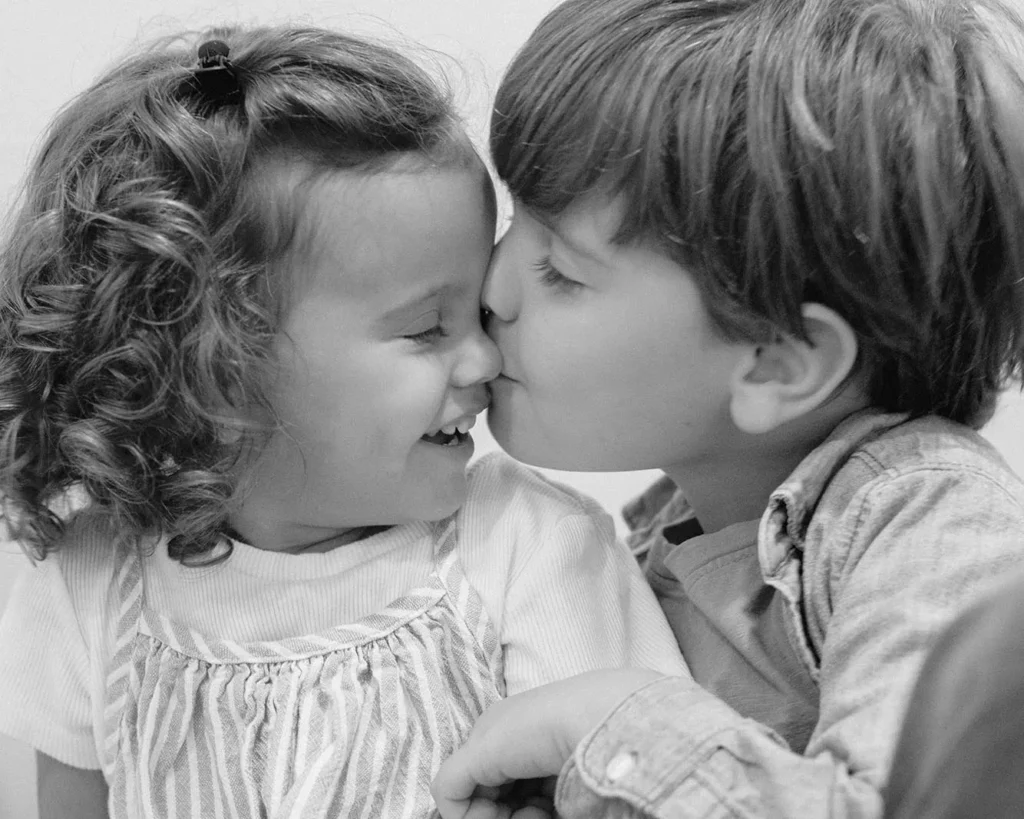 Black and white close-up of a brother kissing his sister during a family session in Fort Lauderdale.