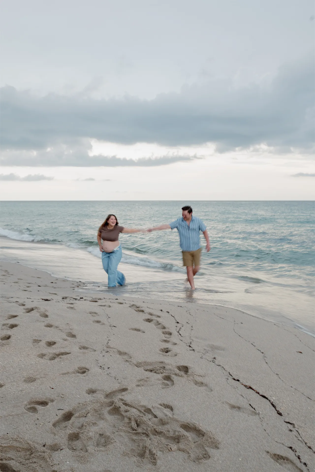 Candid and joyful moments of parents to be during a beachside session