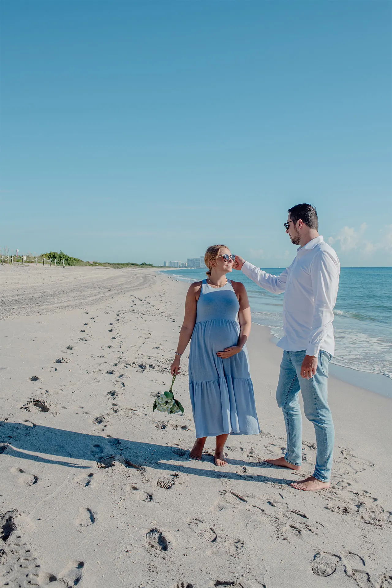 Portrait of an expectant mother and her husband on the beach shore during their pregnancy shoot