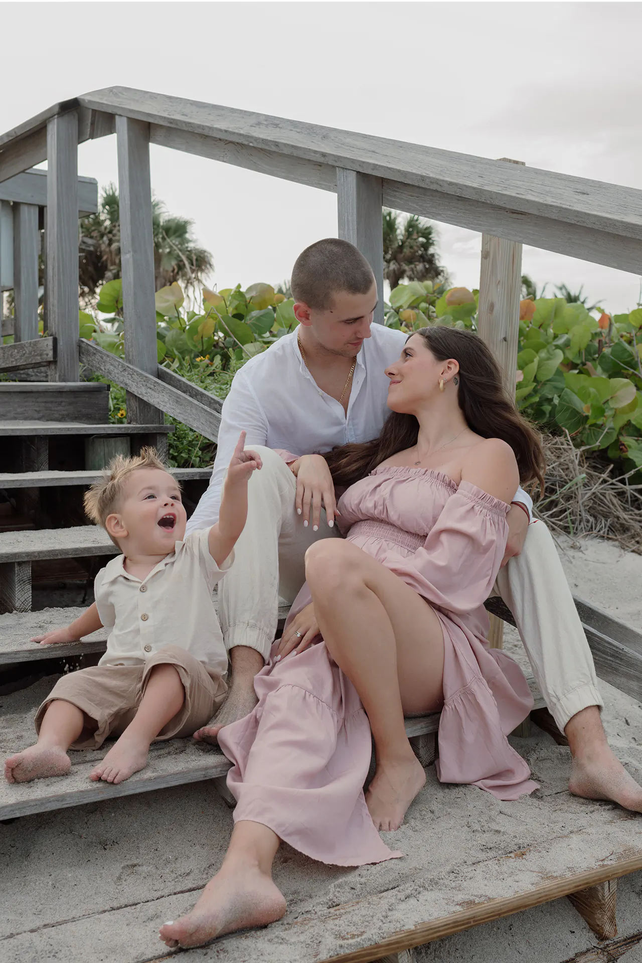 Family portrait of three sitting by the wooden steps of a pier at Dania Beach during sunset