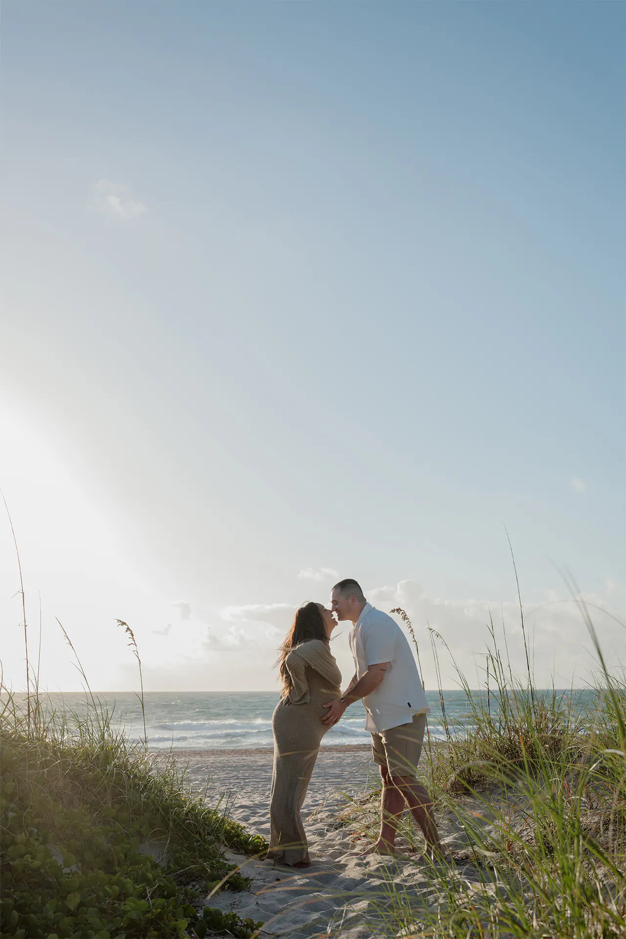 Joyful couple laughing and hugging the belly during their Lauderdale-by-the-Sea session