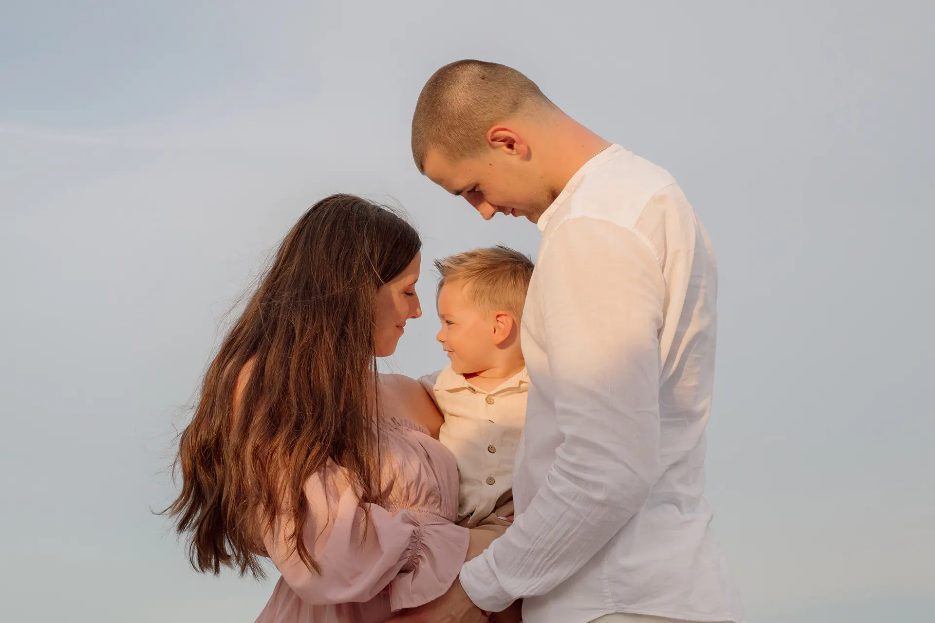 Maternity photographer in Dania Beach capturing a family of three during a golden hour sunset session