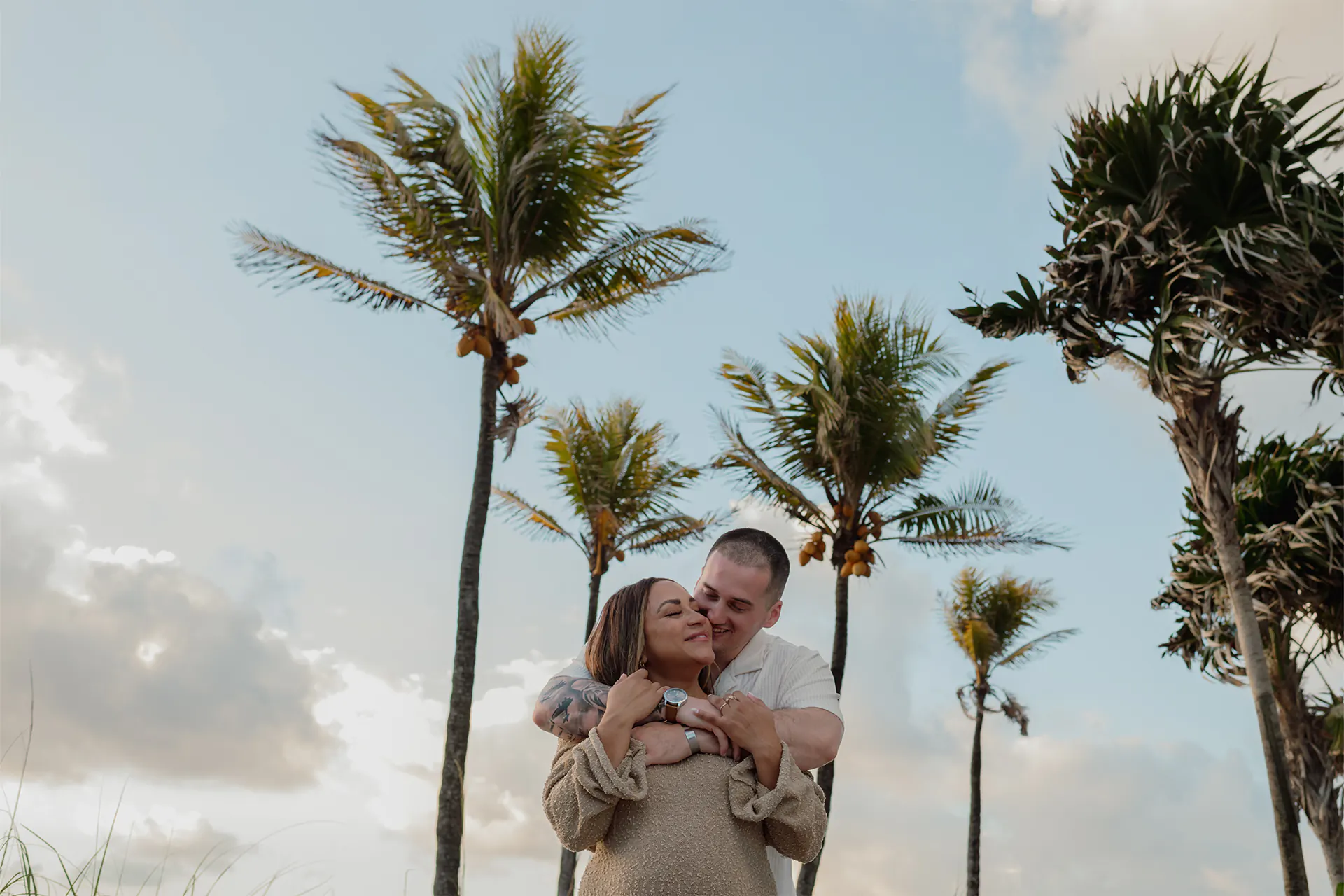 Maternity photographer in Lauderdale-by-the-Sea featuring a couple hugging at sunrise with palm trees