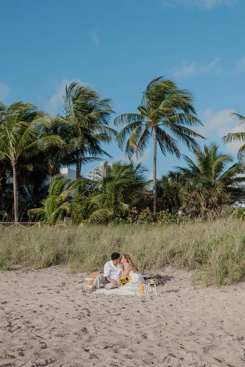 Newly engaged couple kissing and enjoying a beach picnic at Vista Park in Fort Lauderdale