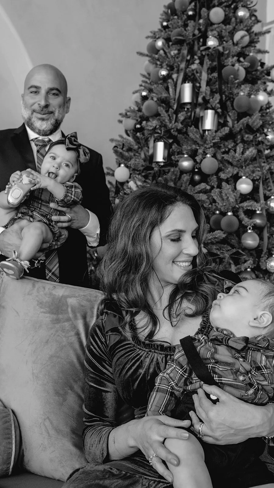 Black-and-white family portrait with young children beside a Christmas tree