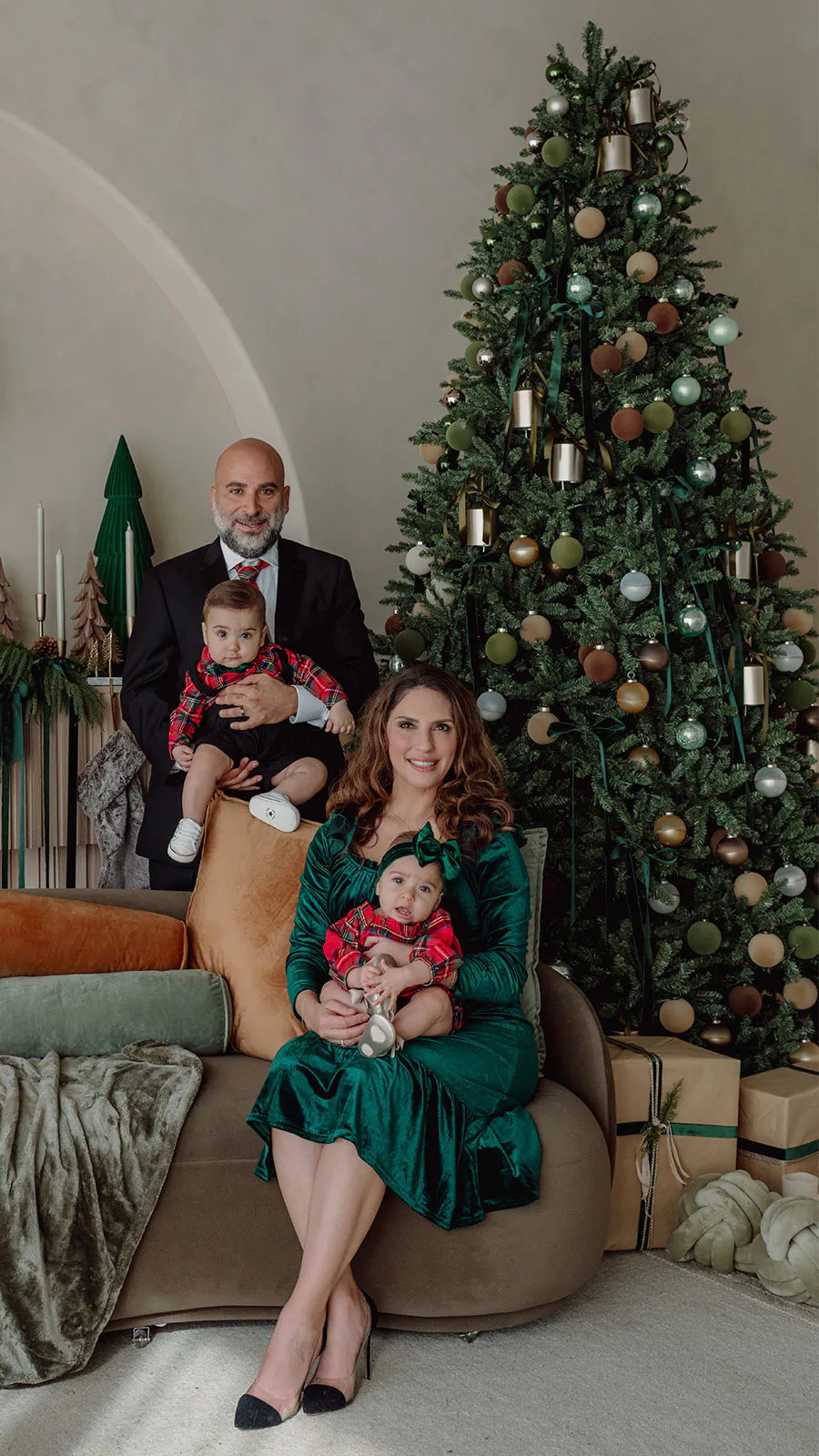 Family of four posing beside a Christmas tree during a holiday photo session